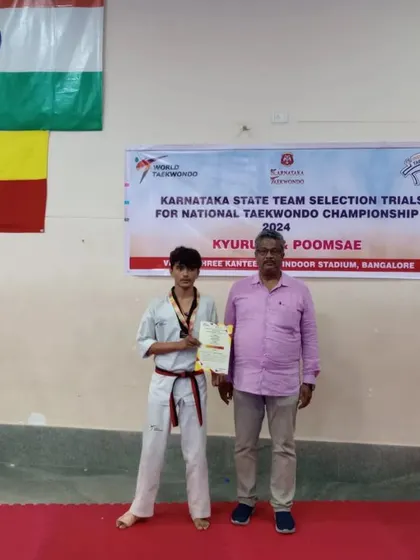 A proud moment for this student, standing with his certificate under the Indian and Karnataka flags.