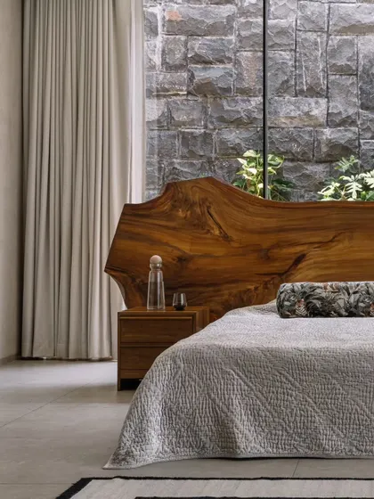 In our GAIA project in Chennai, we designed this master bedroom to be a serene retreat. The live-edge wood headboard brings a raw, natural element indoors, set against a rugged stone wall that connects the space to the earth, reflecting our modern organic and Wabi-Sabi design principles.