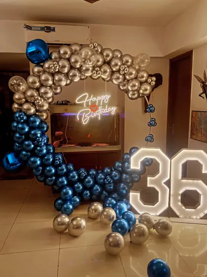 A 36th birthday decoration featuring a square balloon frame in blue and silver chrome, a neon sign, and large light-up numbers.