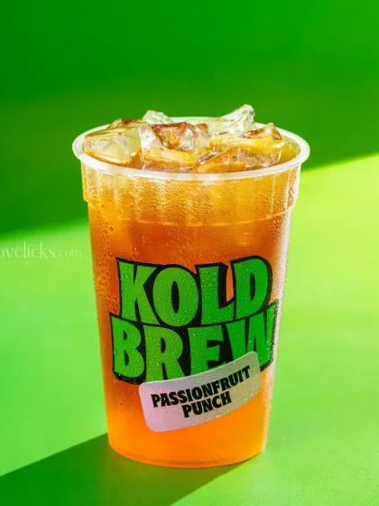 A passionfruit punch iced tea, shot with bright, sunny lighting against a green background.