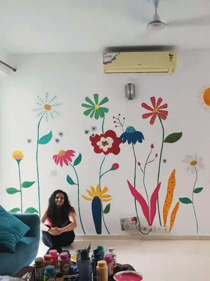 A photo of me with the vibrant floral mural, surrounded by my paints. This shows the joy of completing a piece that brings so much color into a home.