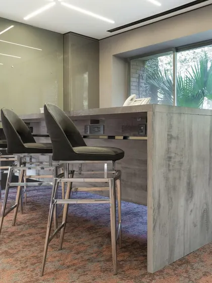 This breakout area features a custom-designed high-top counter, providing an informal space for employees to connect. The wood-textured finish of the counter and the sleek bar stools create a contemporary yet warm corner within the office.