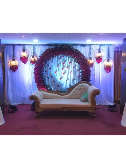 A beautiful stage setup with a floral ring backdrop for a puberty or half-saree function.