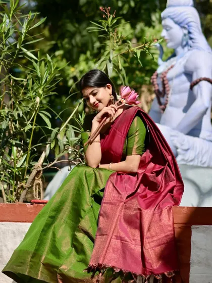 A beautiful moment captured during a half-saree shoot, sitting beside a statue of Lord Shiva. The image has a calm, devotional quality, blending fashion with spirituality.