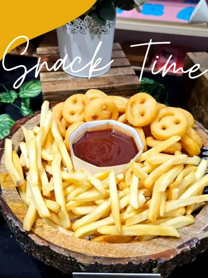 Snack time! A rustic wooden bowl filled with crispy french fries and smiley-faced potato snacks, served with ketchup.