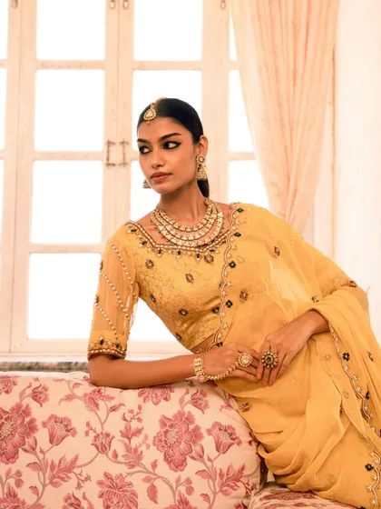 An elegant portrait using soft, natural light to highlight the details of the yellow ethnic wear. The model's relaxed pose creates a graceful and timeless look.
