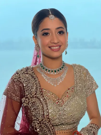 A smiling portrait of my bride by the water. The makeup is fresh and luminous, with a pop of emerald from her jewelry adding a touch of color.