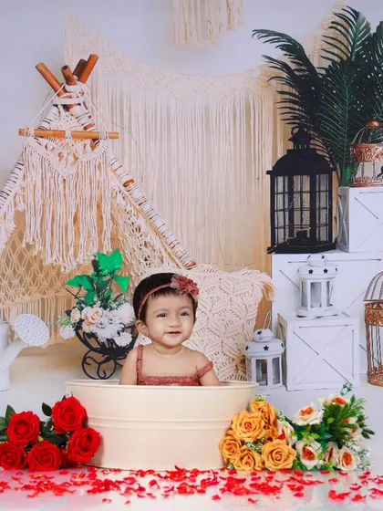 A smiling baby in a tub, surrounded by flowers and boho-decor. This shot captures the pure joy and innocence of childhood in a beautifully styled setting.