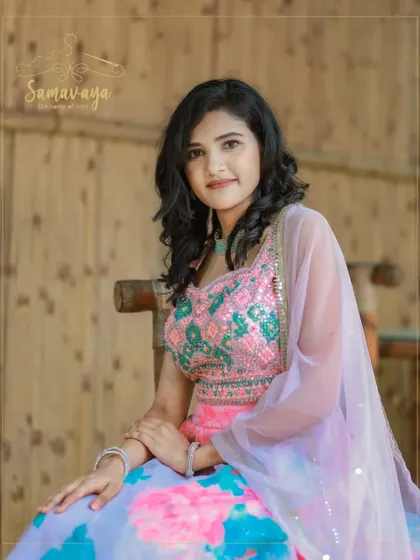 A close-up that highlights the beautiful embroidery of the lehenga blouse and the model's serene expression in a natural setting.