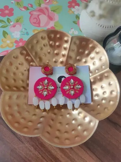 These bright pink hand-painted earrings are perfect for adding a pop of colour to your festive attire. They are decorated with kundan work and feature white bead drops.