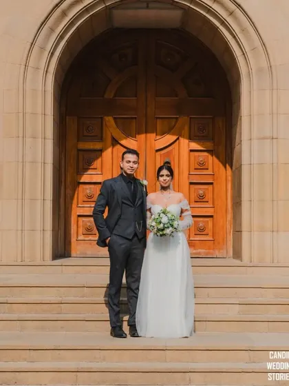 A striking portrait of the bride and groom standing in front of the grand wooden doors of the church, a powerful and symbolic image of their union.