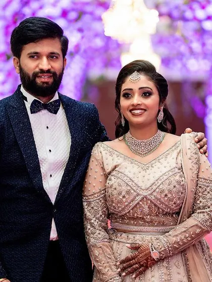 A classic portrait of the couple at their reception, posing against a beautifully decorated purple backdrop.