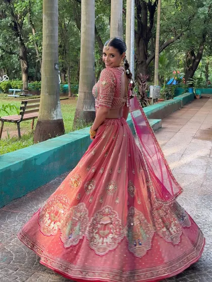 A full-length shot of the bride, showing off her stunning pink lehenga and intricate braid.