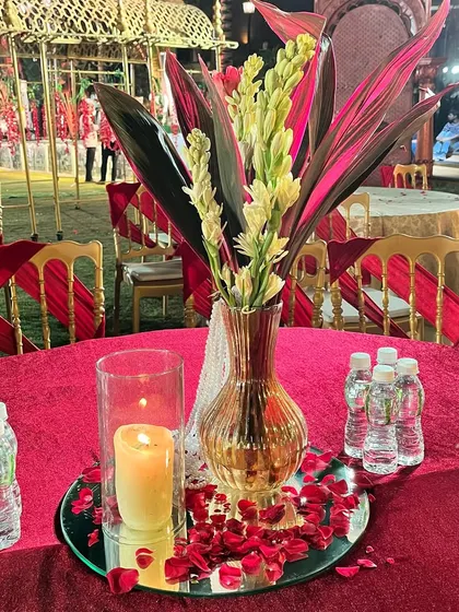 Even the table centerpieces are designed to match the theme. A simple yet elegant arrangement of florals and a candle, set on a mirrored base with scattered petals, adds a touch of romance to the guest tables.