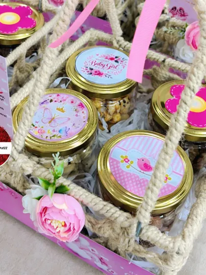 A top-down view of a jute announcement basket, showing the custom-designed lids on the treat jars, each with a unique pink floral or butterfly design.