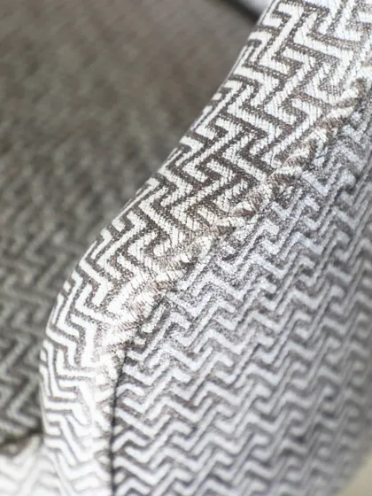 A close-up of a textured, geometric fabric used on one of our custom chairs. We believe the tactile quality of a piece is just as important as its visual form, adding depth and comfort.