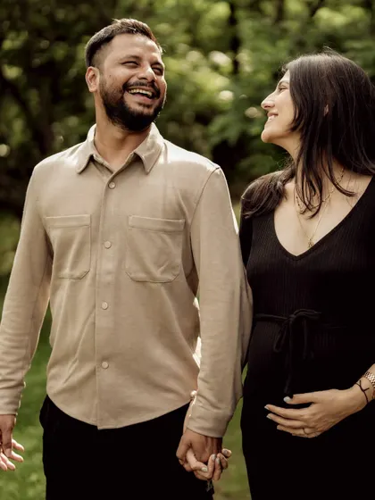 A candid shot of the couple sharing a laugh while walking through the woods. This photo is full of life, joy, and natural connection.