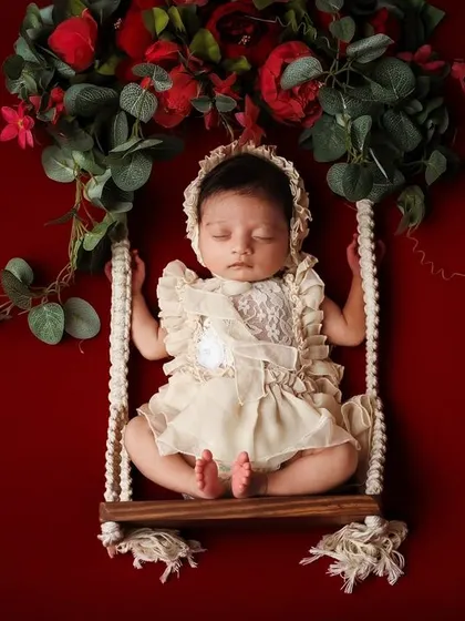 This elegant swing prop, adorned with a floral garland against a rich red backdrop, creates a beautiful and artistic composition.