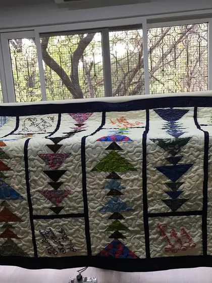 A "Flying Geese" quilt on a longarm quilting frame, ready for its finishing touches.