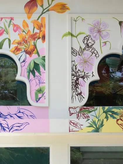 Another detail of the restaurant facade, showing how the floral motifs are integrated with the traditional arched window frames. The mix of styles and colors reflects a modern take on cultural heritage.