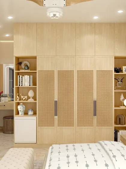 This bedroom in Mr. Aniketh's residence features custom-built wardrobes with cane webbing and open shelving. The design reflects an Indian-bohemian style, blending natural textures with light wood tones for a bright and airy feel.