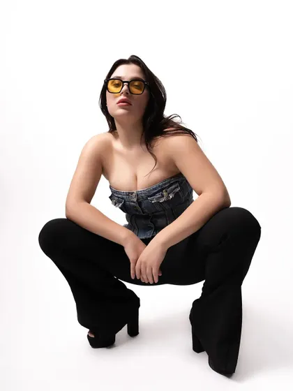 A powerful, low-angle shot from a studio fashion session. This perspective adds drama and confidence, highlighting the flared pants and the model's strong pose.