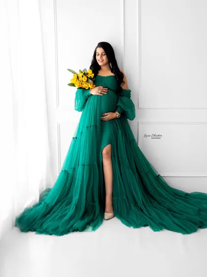 This mom-to-be holds a bouquet of yellow flowers, which provides a lovely, bright contrast to her elegant green gown.