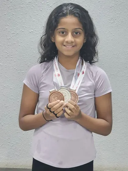 Janya proudly displays her silver and bronze medals from the Candor swimming competition, celebrating her success in freestyle, backstroke, and relay events.