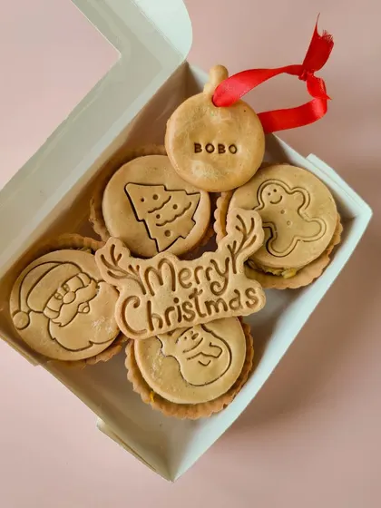 My Christmas Pies Box contains four wholesome pies with cute festive designs like Santa, a snowman, and a Christmas tree. Each box includes a 'Merry Christmas' cookie and a name tag ornament.