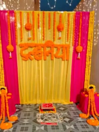A unique 'Dulhaniya' themed backdrop for a bridal shower or Mehendi, using pink and yellow drapes with marigold garlands.