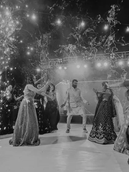 A black and white shot of guests dancing under stage lights and cold pyro effects.