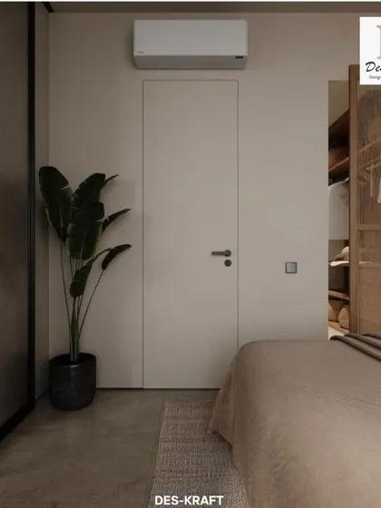 A flush, handleless door and a large potted plant maintain the room's minimalist aesthetic, proving that simplicity is key to a peaceful space.