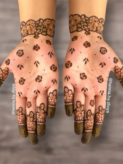 This fancy henna design is perfect for a party. It features scattered floral bootis on the palm with more detailed floral work on the fingers and a matching cuff, combining simplicity with intricacy.