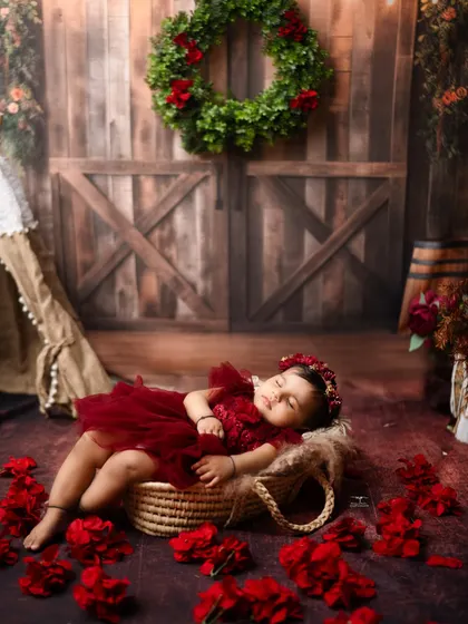 Dreaming among red petals. This little one is nestled in a basket, creating a beautiful, colour-rich image with a rustic feel.