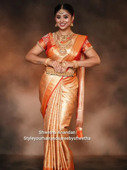A classic bridal pose showcasing the full effect of a perfectly draped Kanjivaram saree. The pleats are set to fall gracefully, and the side sculpting ensures a flattering fit.