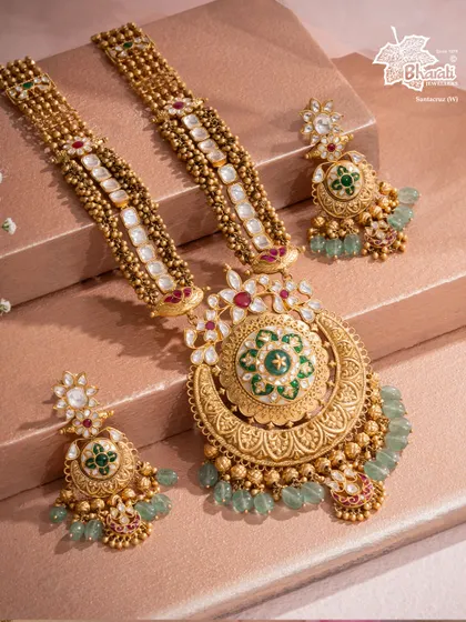 Born from the ocean and crowned in gold, this Mother of Pearl Takkar studded royal necklace is an ode to regal craftsmanship. The large, crescent-shaped pendant features intricate carving and a central mother-of-pearl element, creating a powerful statement of divine femininity.