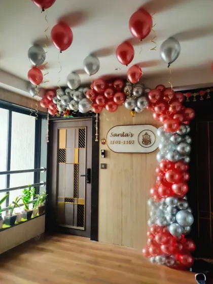 A balloon arch in red and silver around a doorway, creating a grand entrance for a birthday party at home.