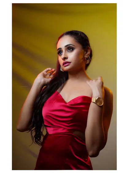 A close-up portrait with dramatic, warm lighting, highlighting the model's features and the texture of the red dress.