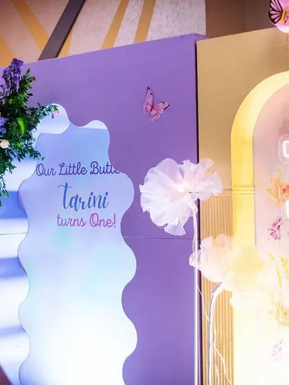 A creative backdrop featuring a wavy mirror and a custom "Our Little Butterfly" sign. I love playing with different shapes and materials to create unique and modern designs.
