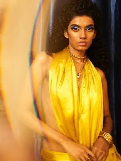 A high-fashion look featuring a dramatic blue eye and glowing skin, captured with an artistic lens flare. This is an example of combining bold color with a flawless base.