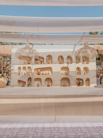 The main backdrop for the Haldi ceremony, featuring a custom-built wall with multiple arches and niches for displaying small decorative items, flanked by large urns with floral arrangements.