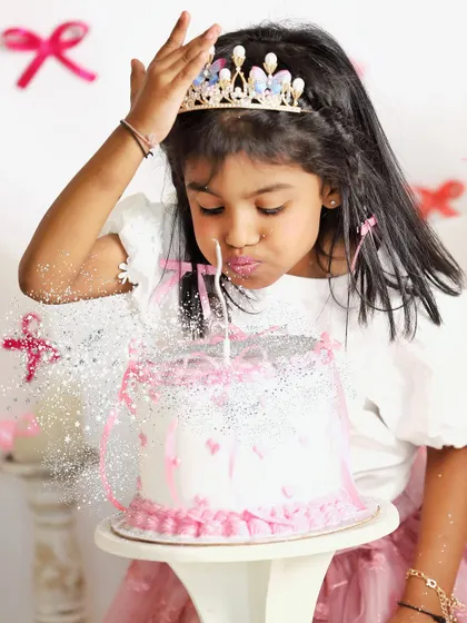 Making a wish. This magical shot captures a little girl blowing glitter from her birthday cake during her princess-themed fifth birthday photoshoot.
