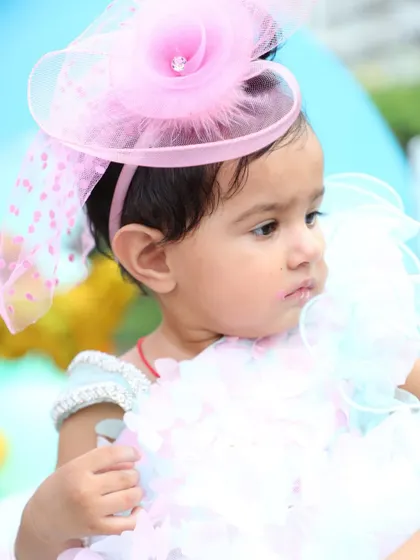 A close-up portrait of the birthday girl in her beautiful party dress and fascinator. I focus on capturing these details, from the outfit to the little smudge of cake on her lip.