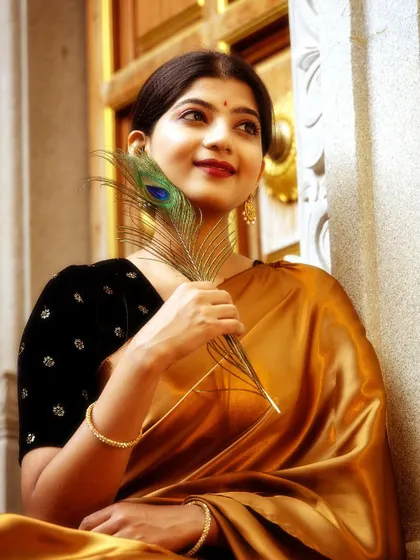Holding a peacock feather, this shot in a gold satin saree was taken at a temple entrance. The feather adds a touch of symbolism, connecting to Lord Krishna and divine beauty.