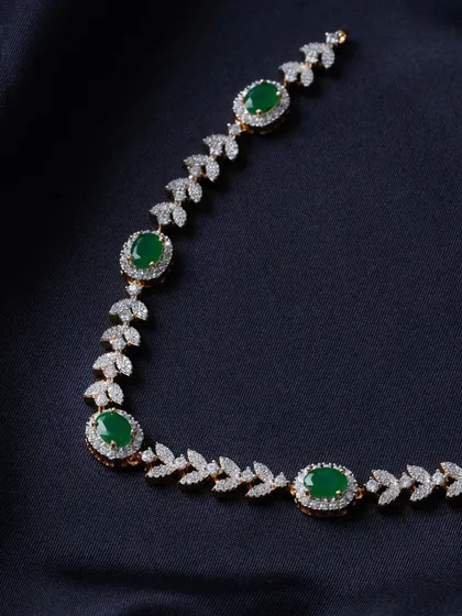 A sophisticated necklace designed with leaf-shaped American Diamond motifs and oval green stones. The combination of sparkling white and deep green gives this piece a look of pure luxury.
