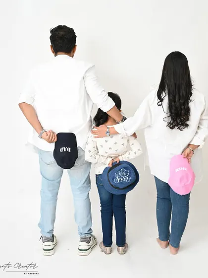 A creative and fun family announcement. The matching hats add a playful touch to this unique family portrait, revealing their roles as 'Dad,' 'Mom,' and 'Big Sister.'