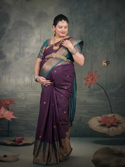 A portrait of quiet elegance. The mom-to-be, dressed in a purple saree, stands against a backdrop of a lotus pond, creating a serene and artistic image.