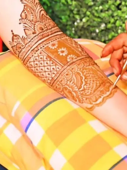 A close-up of the work in progress, showing the fine details of a peacock feather pattern.