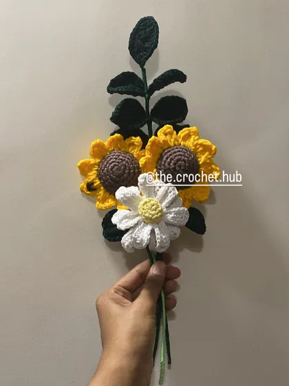 A simple and beautiful arrangement of two sunflowers and a daisy, ready to be wrapped.