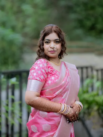 A close-up portrait of a bride in a lovely pink saree, showcasing her intricate mehndi and gentle expression.